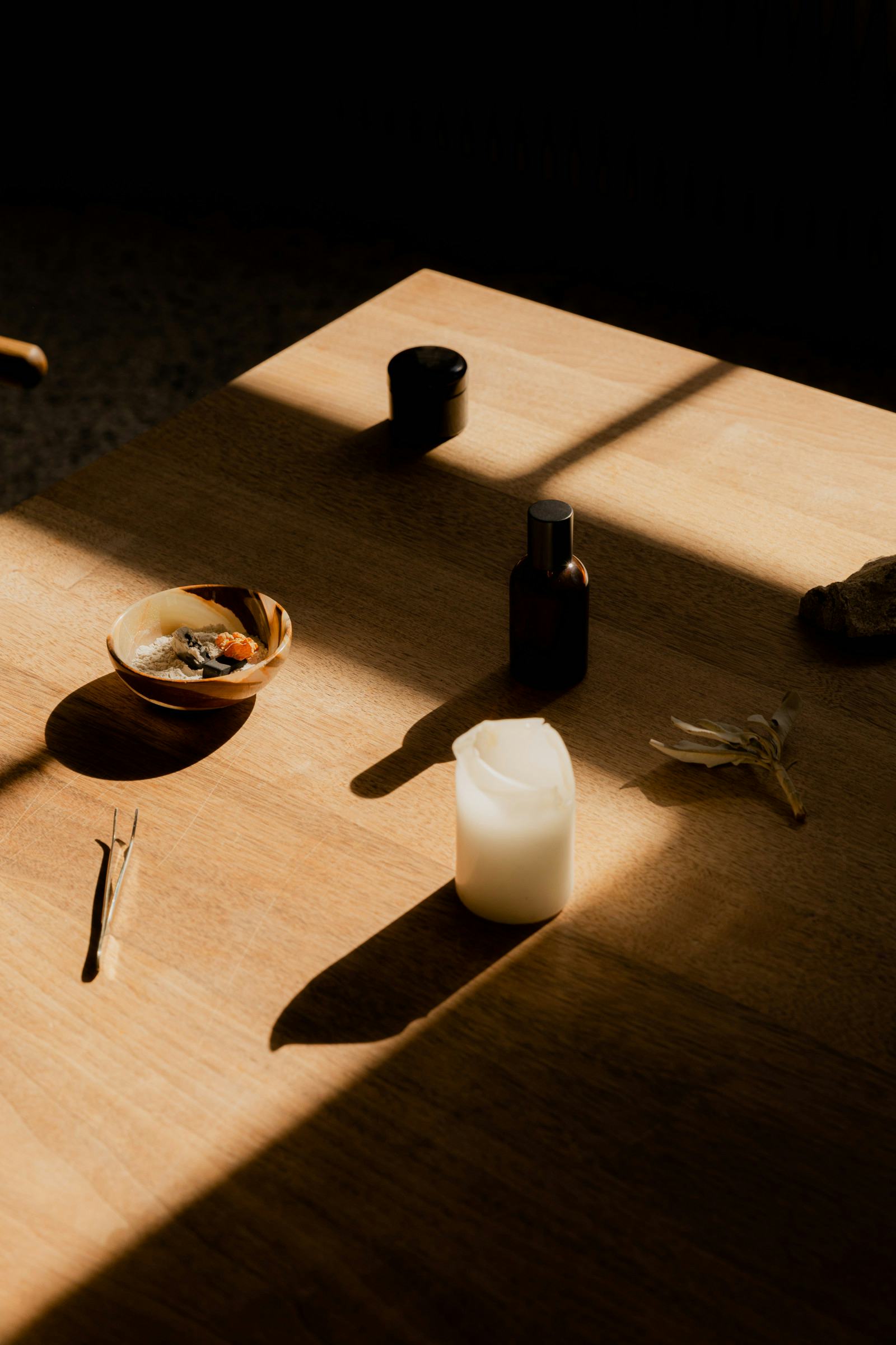 Matchu Matcha Image of Wooden table with a candle, bottle, and small bowl in soft light
