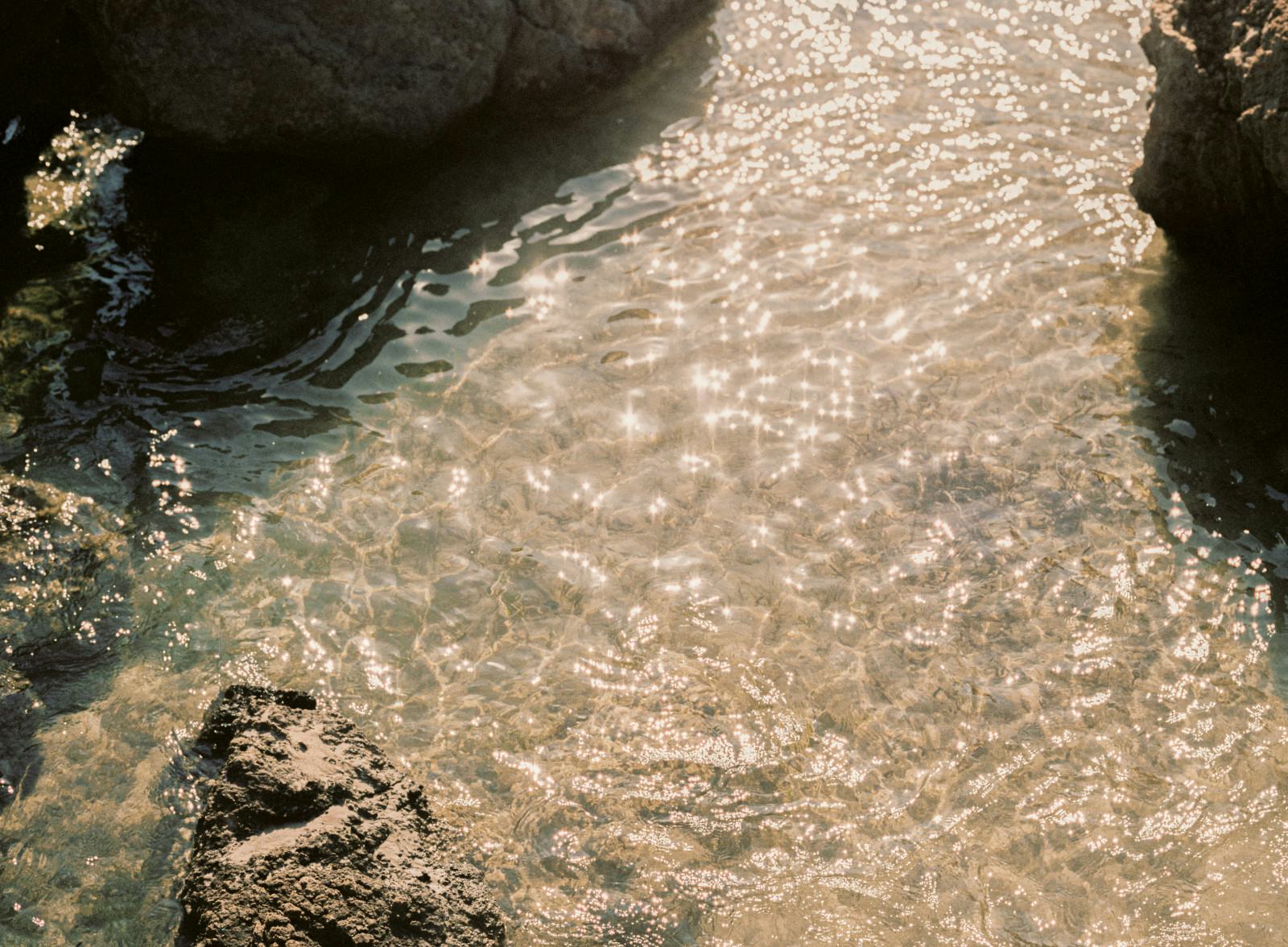 Matchu Matcha Image of Clear water with sunlight reflecting off the surface near rocks